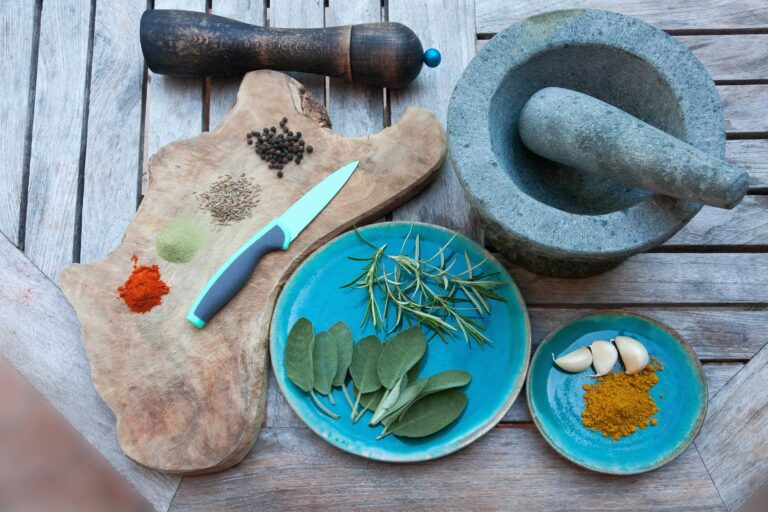 A Chopping board with knife, two plates with garlic, turmeric, and other spices for preparing an herbal remedy.