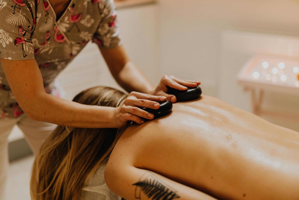 A man massaging a woman's back with a gua sha stone.