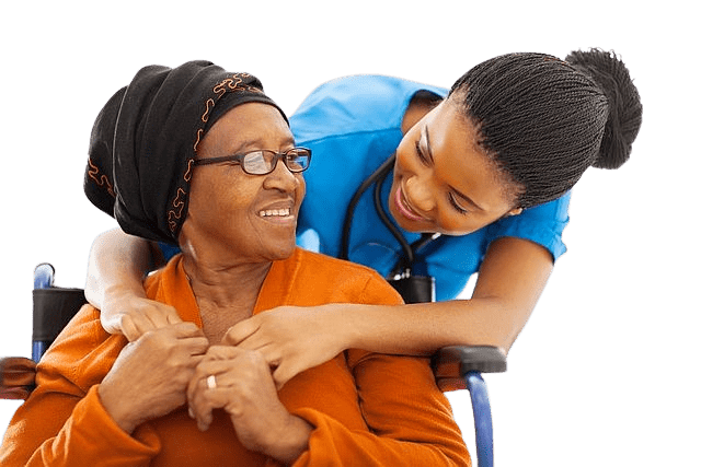 An elderly woman in a wheelchair smiles at a young Black nurse who has her arm around her neck.