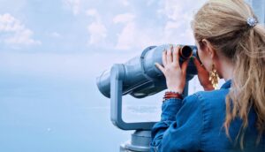 A woman looking through a telescope, symbolizing looking into the future.